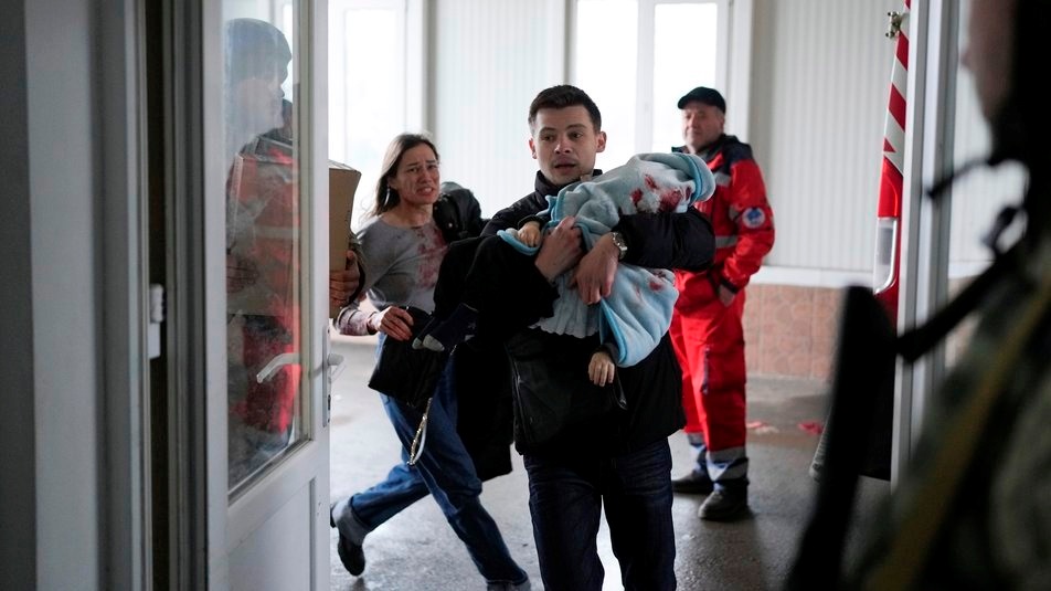 Жінка біжить за своїм хлопцем, який несе 18-місячного загиблого сина у лікарню під час обстрілів у Маріуполі. Дитина загинула. 4 березня 2022